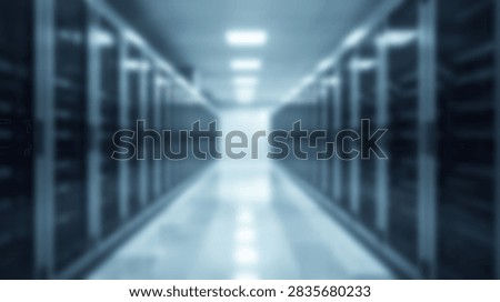 A blurred perspective view down a long aisle in a modern data center server room, illuminated by overhead lights.