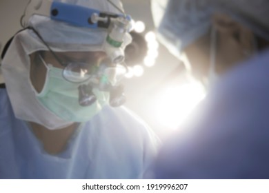 Blurred Photo For Background.Team Of Doctor Working Inside Modern Operating Room.Advanced Plastic Surgery Procedure.Surgeon Wearing Surgical Loupe Magnify Glasses.