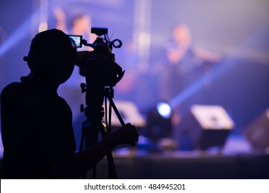 Blurred photo of Cameraman silhouette on a concert stage
