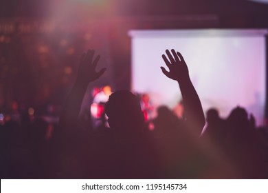 Blurred photo of Christian worship God together in Church hall in front of music stage.raised hand and praise the LORD.Music concert background.