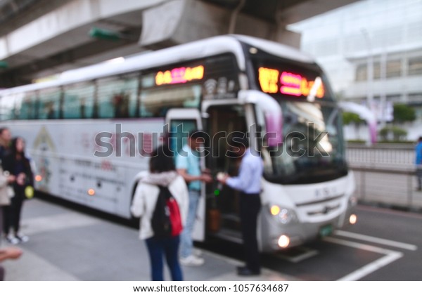 The blurred photo of getting on the bus. The bus\
driver is checking traveler\'s ticket.  The cityscape of\
transportation in Taipei,\
Taiwan.