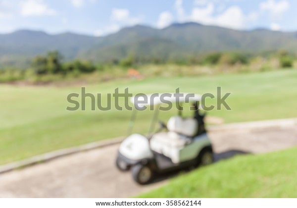 Blurred photo of golf cart parks around golf\
course service standby for\
golfers.