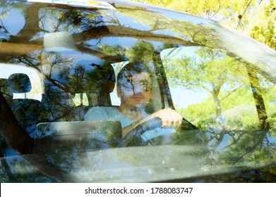 Blurred Photo Of Man Driving Car Seen Through Windshield. Solo Travels. Glare On Glass