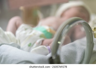 Blurred Photo Of A Newborn Baby Is In The Glass Incubator Box At Hospital Nursery Room. Medical Of Newborn Life For Blurred Background.