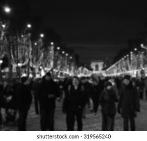 Blurred photo of people promenade at Champs Elysees with Christmas festive illumination and Arch of Triumph seen at background. Paris in winter. Aged photo. Black and white photography.