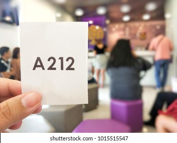 Blurred Photo Of People Showing Queue Ticket While Waiting For The Service At The Bank