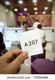 Blurred Photo Of People Showing Queue Ticket For Transferring Money At The Bank