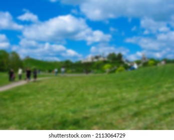 Blurred Photo. People Walk In The Botanical Garden On A Beautiful Sunny Day. People Are Walking In The Park. 