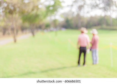 Blurred Photo Of Two Spectators Are Looking The Match In Golf Tournament. 