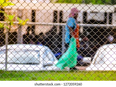 Blurred Photography Of Trash Keeper Holding The Green Plastic Bag Behide Steel Wire Mesh Fence Wall.Recycle Trash Bag.