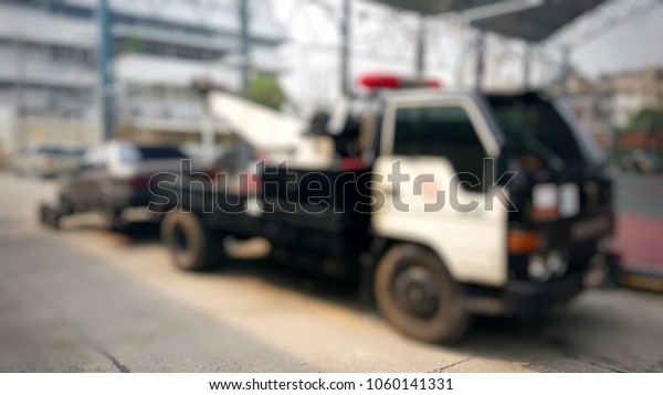 Blurred a police department tow\
truck are towing bronze vehicle are broken on the road to prevent\
the danger of accidental duplications and delivers to the\
garage