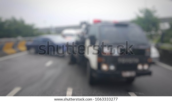 Blurred a police department tow\
truck are towing blue vehicle are accident on the road to prevent\
the danger of accidental duplications and delivers to the\
garage