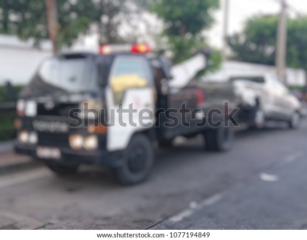 Blurred a police\
department tow truck are towing bronze vehicle are accident on the\
road to prevent the danger of accidental duplications and delivers\
to the garage
