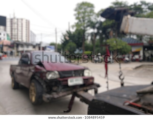 Blurred a police department tow\
truck are towing red vehicle are accident on the road to prevent\
the danger of accidental duplications and delivers to the\
garage
