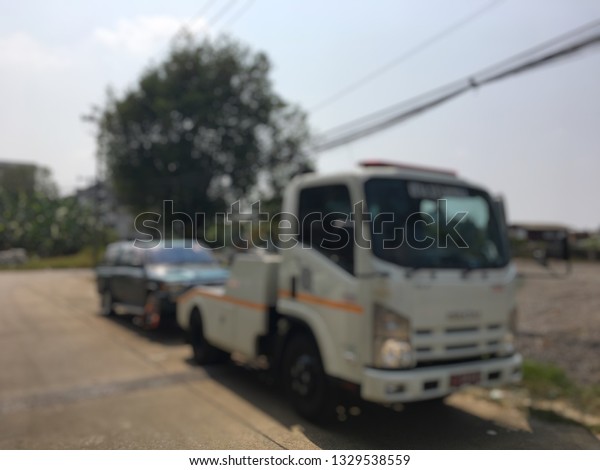 Blurred of police department tow truck are\
towing green vehicle are broken on the road to prevent the danger\
of accident duplicate and deliver to the\
garage