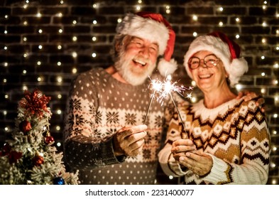 Blurred portrait of senior couple in Santa hat holding sparkler lights. Celebration Xmas and new year concept - Shutterstock ID 2231400077