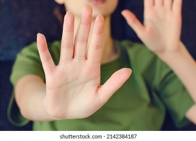 Blurred portrait of young lady extending hand forward saying no enough. Focus on female palm close up raised in prohibiting gesture. shows stop sign prohibition symbol keeps palm forward to camera.