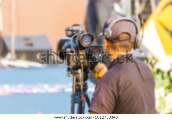 blurred - professional cameraman -\
covering an event to a live and record video at\
outdoor