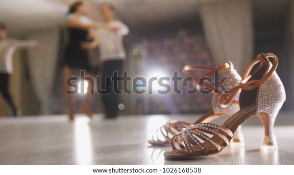 Blurred\
professional man and woman dancing Latin dance in costumes in the\
Studio, ballroom shoes in the\
foreground