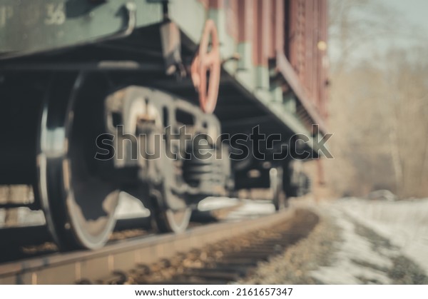 Blurred railway freight wagon stands on\
an alternate track. The lower part of the car with a close-up of\
the wheelset. Cargo wagon. Iron wheel.\
Defocused