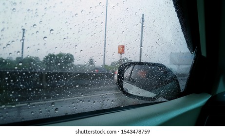 Blurred rain drop on the car glass with city background, water drops at the car window.