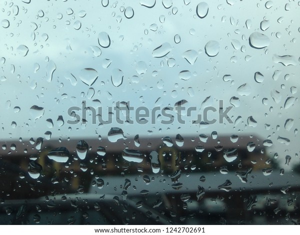 Blurred rain drop on the car glass\
background, water drops at the car window driver\
side