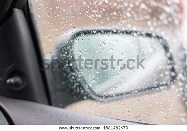 Blurred rain drop on the car glass\
background, water drops at the car window driver\
side.