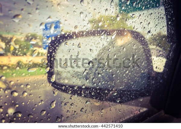 Blurred rain drop on\
the car glass background, water drops at the car window driver\
side, vintage color