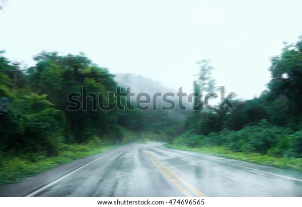 Blurred raining road in\
forest background
