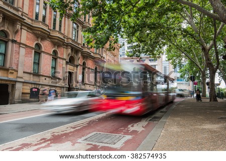 blurred red bus and car on one of the sydney streets during the day