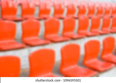 Blurred red empty plastic seats of a little stadium. Horizontal blur background