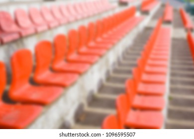 Blurred red empty plastic seats of a little stadium. Horizontal blur background.