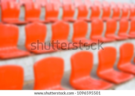 Blurred red empty plastic seats of a little stadium. Horizontal blur background