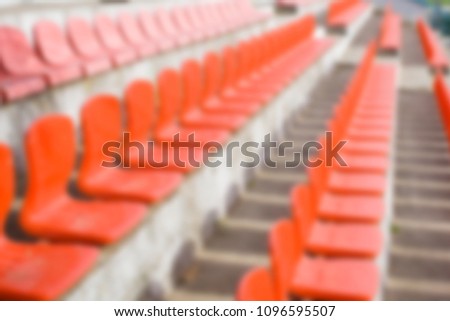 Blurred red empty plastic seats of a little stadium. Horizontal blur background.