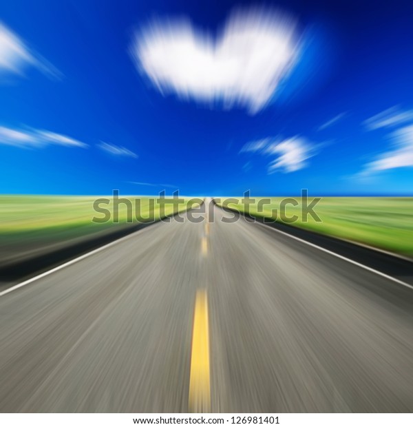 Blurred road and blue motion blurred sky with \
heart shape cloud
