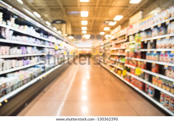 Blurred row of fridge shelves with different\
brands and flavors of yogurt at local store in Humble, Texas, US. \
Variety of yogurt and frozen foods in refrigerator aisle, defocused\
bokeh light.