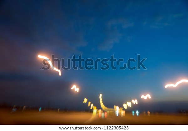Blurred scene of driving at\
night with speed or drunk driver, motion line of electricity light\
on road and led billboard. Abstract background and drive safety\
concept.