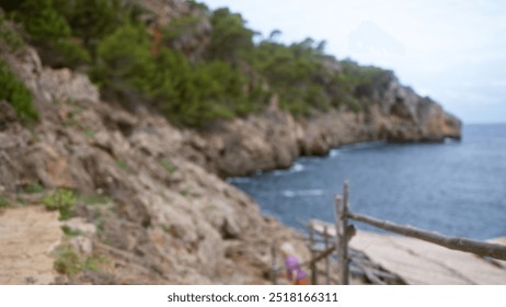 Blurred scene in mallorca with rocky coastline and out-of-focus trees with a woman in the background near the sea shore - Powered by Shutterstock