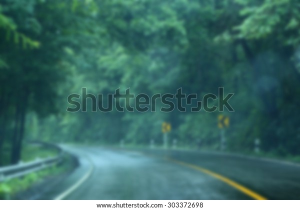Blurred scene\
of wet road in the forest after\
rain.