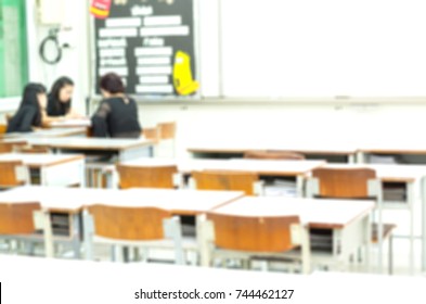 Blurred School Background Of White Classroom And Brown Chairs With Teacher, Student And Parent Talking At Teacher Desk