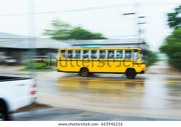 blurred\
school bus  running on the road in raining\
day.
