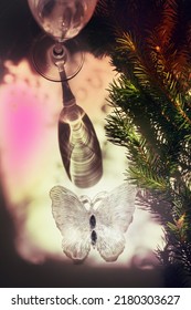 Blurred shadow of wine glass with light passes through glass.  branch of Christmas tree and christmas butterfly toy . Abstract, play of light and shadow, shadow play illusion . Christmas still life