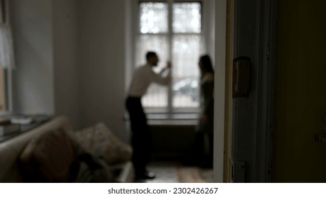 Blurred shot of couple arguing at home. Candid moment of husband and wife fighting each other. Person threatening the other in discussion