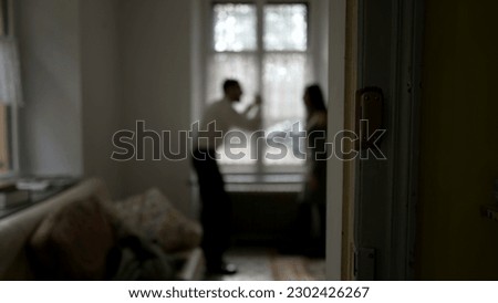 Blurred shot of couple arguing at home. Candid moment of husband and wife fighting each other. Person threatening the other in discussion