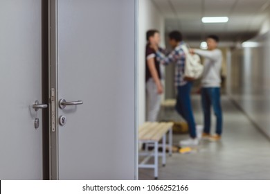 blurred shot of schoolboy being bullied by classmates in school corridor