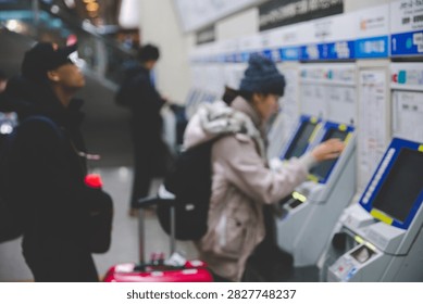 Blurred side view of passengers using ticket vending machines to purchase train tickets at a railway station in Osaka, Japan.