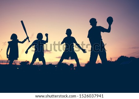 Blurred sihouette kids family holding baseball and american football rise up and playing on sunset background