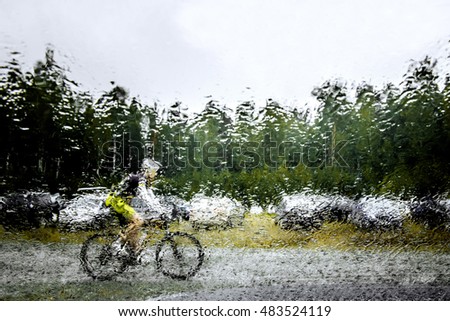 blurred silhouette behind squirt water glass of mountainbiker. autumn rainy weather
