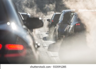 Blurred Silhouettes Of Cars Surrounded By Steam From The Exhaust Pipes. Traffic Jam 