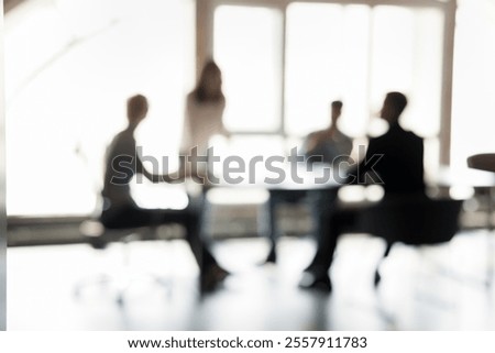 Blurred silhouettes of people participate in business meeting or collaborative discussion, engaged in exchanging ideas, make decisions, strategizing together, gathered in well-lit boardroom. Teamwork